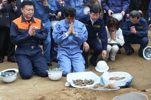 Photograph of the Prime Minister joining his hands in prayer to the remains of the war dead