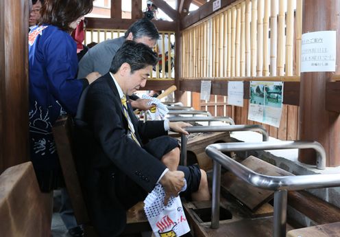 Photograph of the Prime Minister trying out the foot steam bath at the Kannawa hot spring area