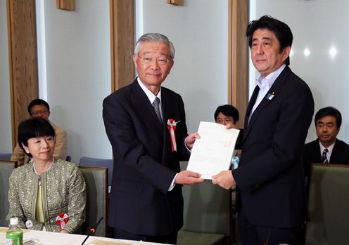 Photograph of Prime Minister Abe receiving a report from the Chair of the Regulatory Reform Council, Mr. Motoyuki Oka