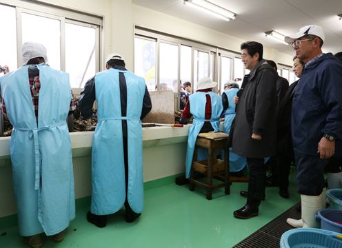 Photograph of the Prime Minister visiting an oyster processing room at the joint oyster processing plant