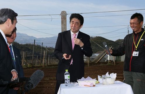 Photograph of the Prime Minister tasting grapes that are a local specialty