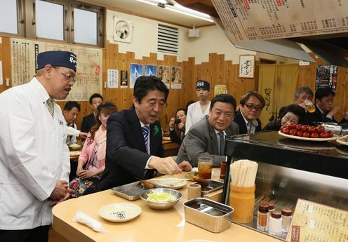 Photograph of the Prime Minister tasting kushikatsu