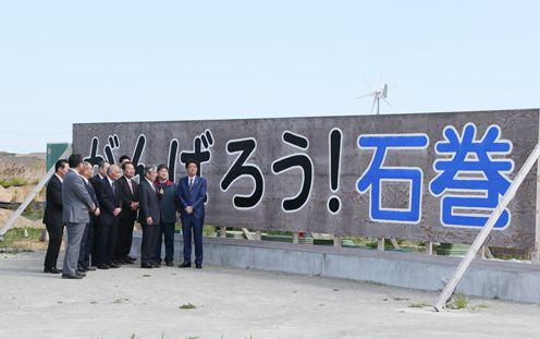 Photograph of the Prime Minister observing the “Ganbaro! (Let’s do our best) Ishinomaki” signboard