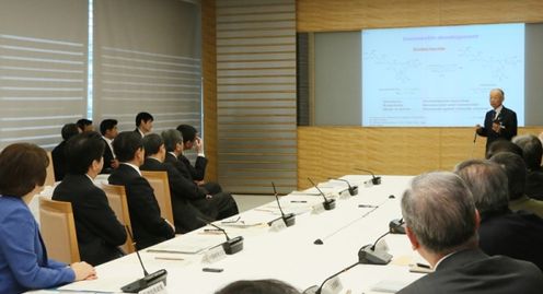 Photograph of the Prime Minister listening to the explanation by Professor Emeritus Satoshi Omura