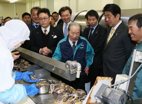 Photograph of the Prime Minister observing oyster shucking