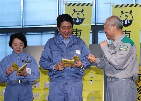Photograph of the Prime Minister being presented with a disaster prevention book from the Governor of the Tokyo Metropolitan Government