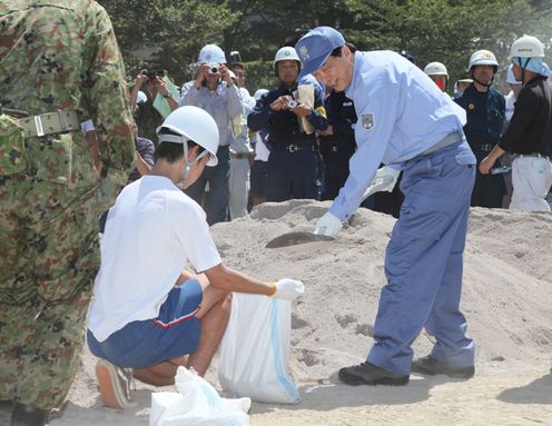 Photograph of the Prime Minister taking a part in sandbag making during comprehensive disaster drills in Shizuoka Prefecture
