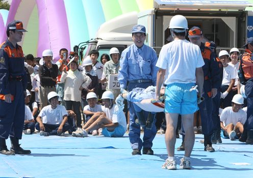 Photograph of the Prime Minister taking part in carrying a person on an instant stretcher during comprehensive disaster drills in Shizuoka Prefecture