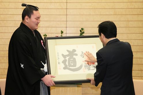 Photograph of the Prime Minister comparing the size of the handprint on the autograph presented as a gift