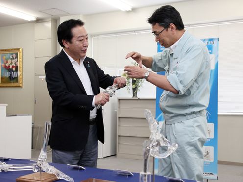 Photograph of the Prime Minister observing an artificial joint product at a company in Okayama City
