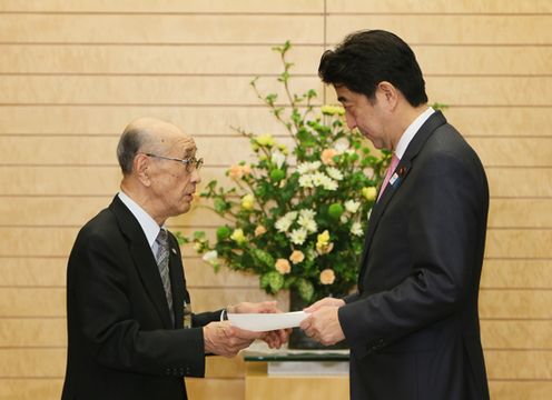 Photograph of Prime Minister Abe receiving a letter of request from Director of the League of Residents of Chishima and Habomai Islands, Mr. Toshio Koizumi