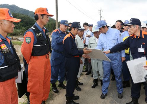 Photograph of the Prime Minister observing a site hit by torrential rain in the Ato-Tokusa-Shimo area in Yamaguchi City (1)
