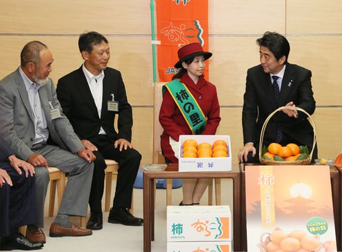Photograph of the Prime Minister receiving an explanation from producers and the Persimmon Village Ambassadors on persimmons