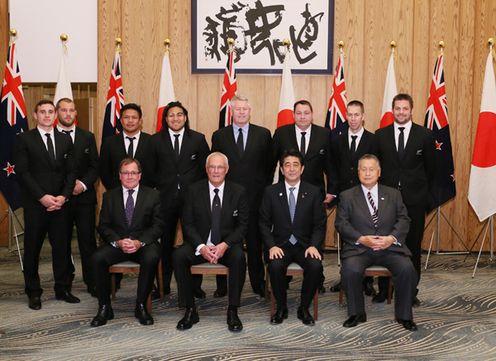 Photograph of the Prime Minister attending a commemorative photograph session with the New Zealand national rugby team, the 