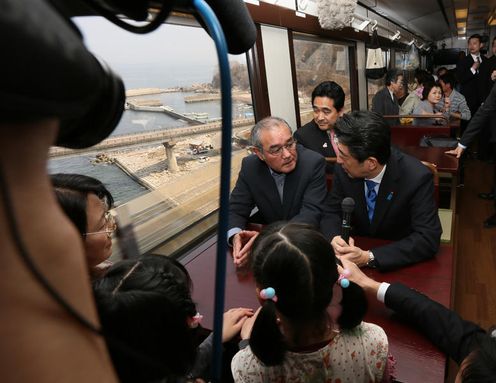Photograph of the Prime Minister conversing with passengers in a railcar of the Sanriku Railway (1)