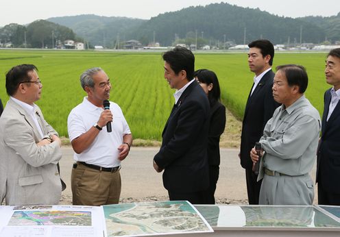 Photograph of the Prime Minister receiving an explanation on the progress of restoration of farmland damaged in the tsunami
