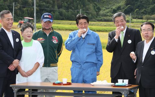 Photograph of the Prime Minister visiting a rice farm and sampling rice