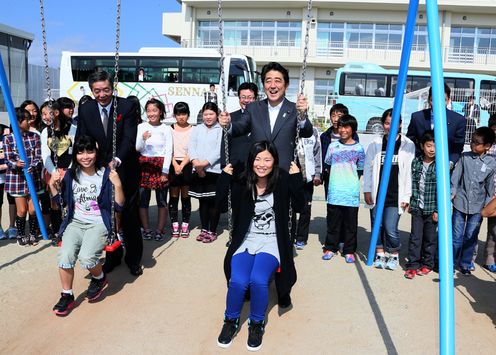 Photograph of the Prime Minister interacting with students  on playground equipment at Nagatoro Elementary School