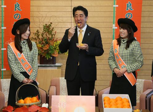 Photograph of the Prime Minister sampling persimmons