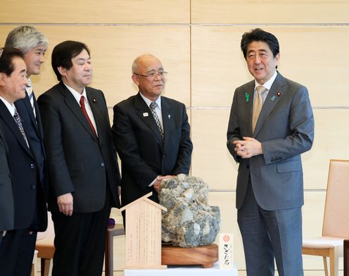 Photograph of the Prime Minister being presented with the gravel boulder