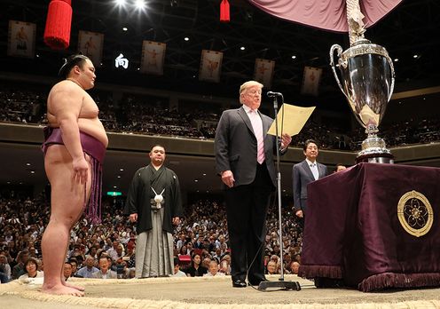 Photograph of President Trump reading a certificate of award