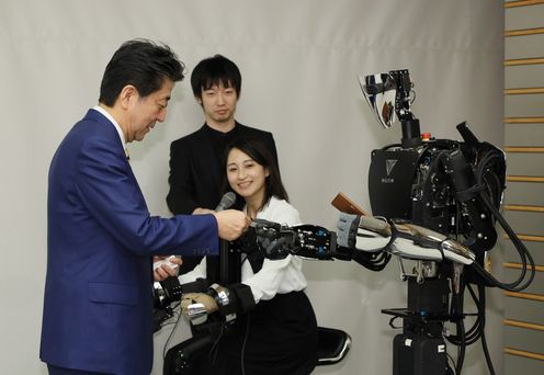 Photograph of the Prime Minister exchanging business cards with a robot