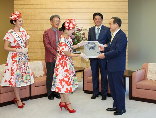 Photograph of the Chief Cabinet Secretary being presented with a kariyushi shirt