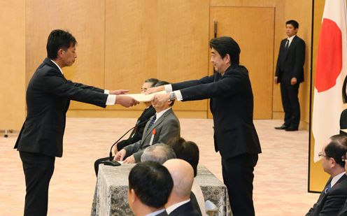 Photograph of the Prime Minister presenting a certificate of award