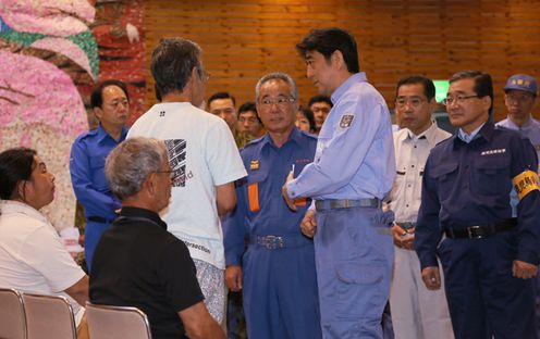 Photograph of the Prime Minister listening to an evacuee