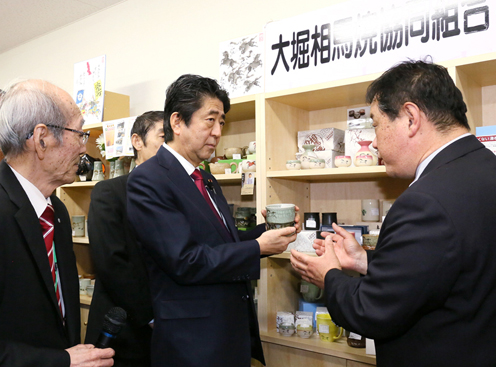 Photograph of the Prime Minister conversing with an individual in the Obori-soma-yaki ceramics business