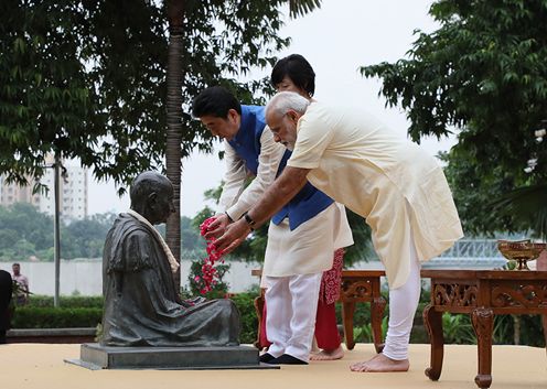 Photograph of both leaders offering flowers at a statue of Mahatma Gandhi