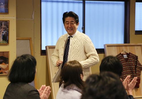 Photograph of the Prime Minister trying on a hand-knit sweater