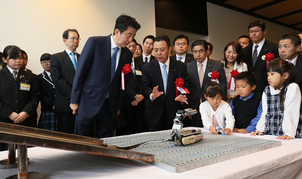 Photograph of the Prime Minister receiving an explanation regarding a robot demonstration at the Naraha Remote Technology Development Center