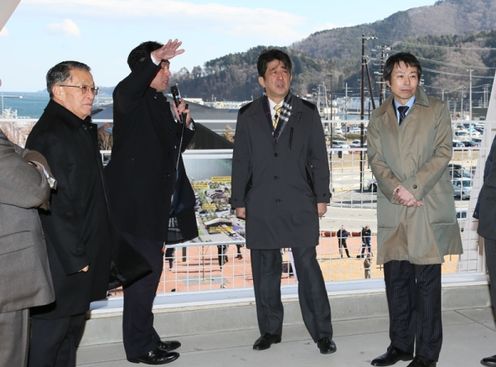 Photograph of the Prime Minister receiving an explanation about the progress of reconstruction from the Mayor of Onagawa Town at the observation deck on the roof of the new train station