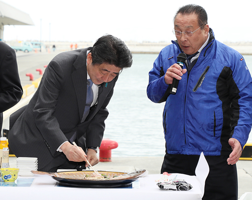 Photograph of the Prime Minister tasting food at the Matsukawaura fishing port (1)