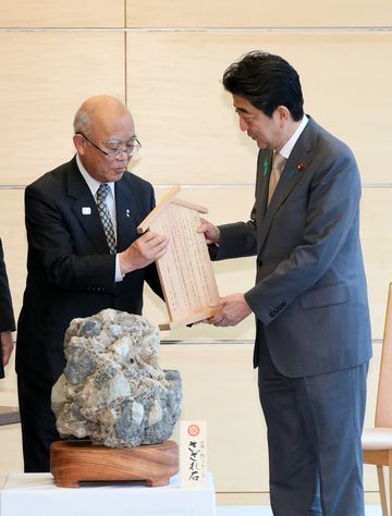 Photograph of the Prime Minister being presented with the gravel boulder