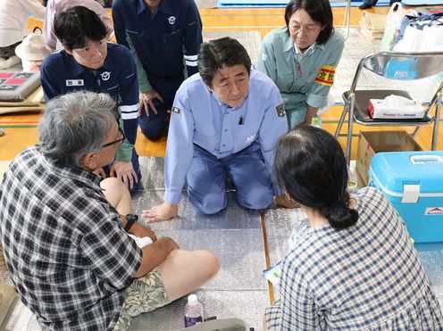 Photograph of the Prime Minister listening to those affected by the disaster