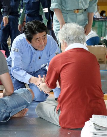 Photograph of the Prime Minister listening to those affected by the disaster