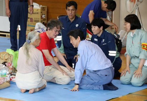 Photograph of the Prime Minister listening to those affected by the disaster