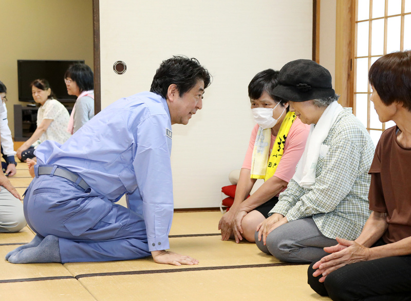 Photograph of the Prime Minister listening to those affected by the disaster