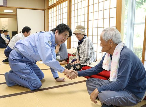 Photograph of the Prime Minister listening to those affected by the disaster