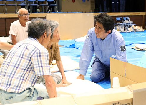 Photograph of the Prime Minister listening to those affected by the disaster