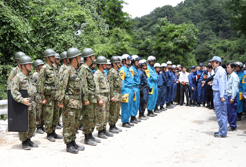 Photograph of the Prime Minister encouraging police department, fire department, and Self-Defense Force units at a site affected by landslide