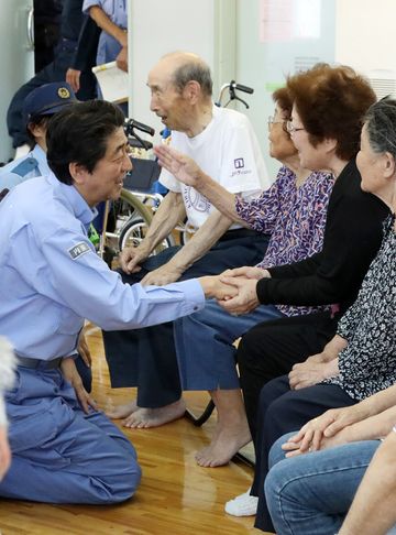 Photograph of the Prime Minister listening to those affected by the disaster