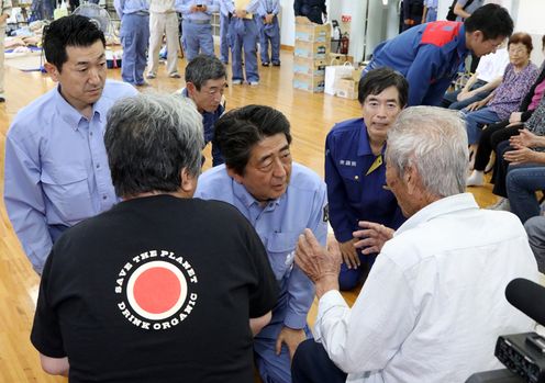 Photograph of the Prime Minister listening to those affected by the disaster