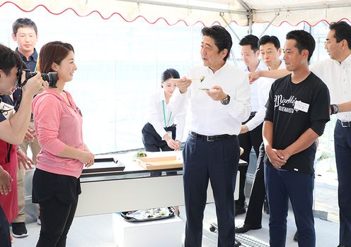 Photograph of the Prime Minister tasting garlic chive and other produce