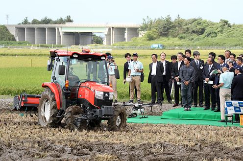 Photograph of the Prime Minister watching a demonstration of the self-driving combine harvester and tractor 