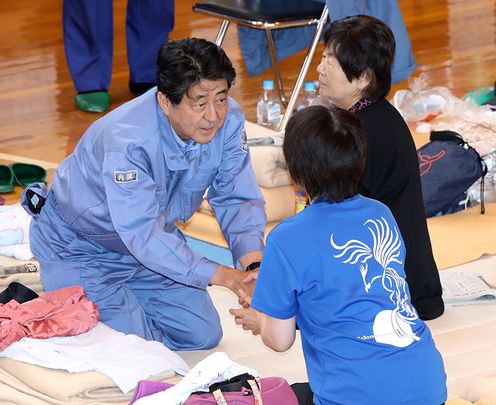 Photograph of the Prime Minister listening to those affected by the disaster at an evacuation center in Atsuma Town