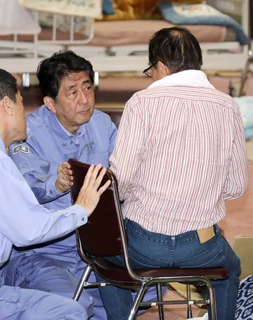 Photograph of the Prime Minister listening to those affected by the disaster at an evacuation center in Abira Town