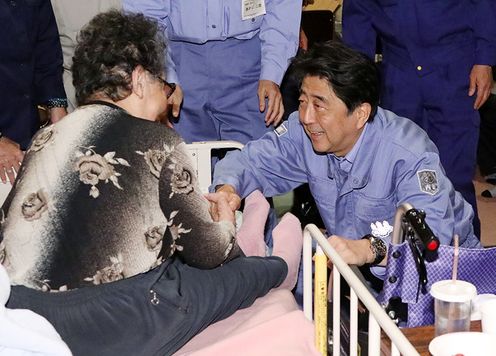 Photograph of the Prime Minister listening to those affected by the disaster at an evacuation center in Abira Town